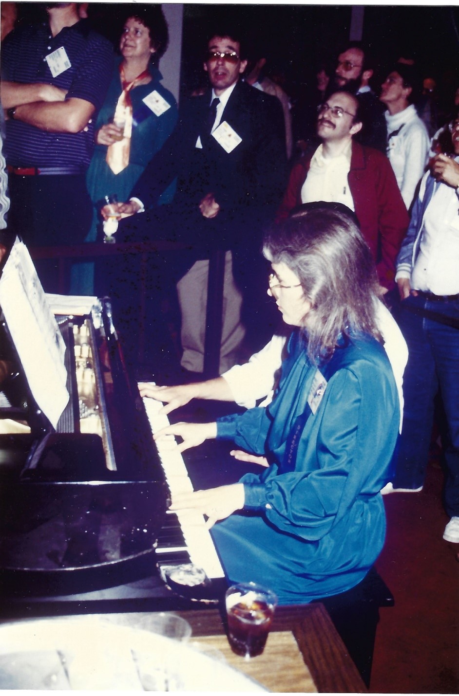 Woman with long brown hair in blue dress playing the piano