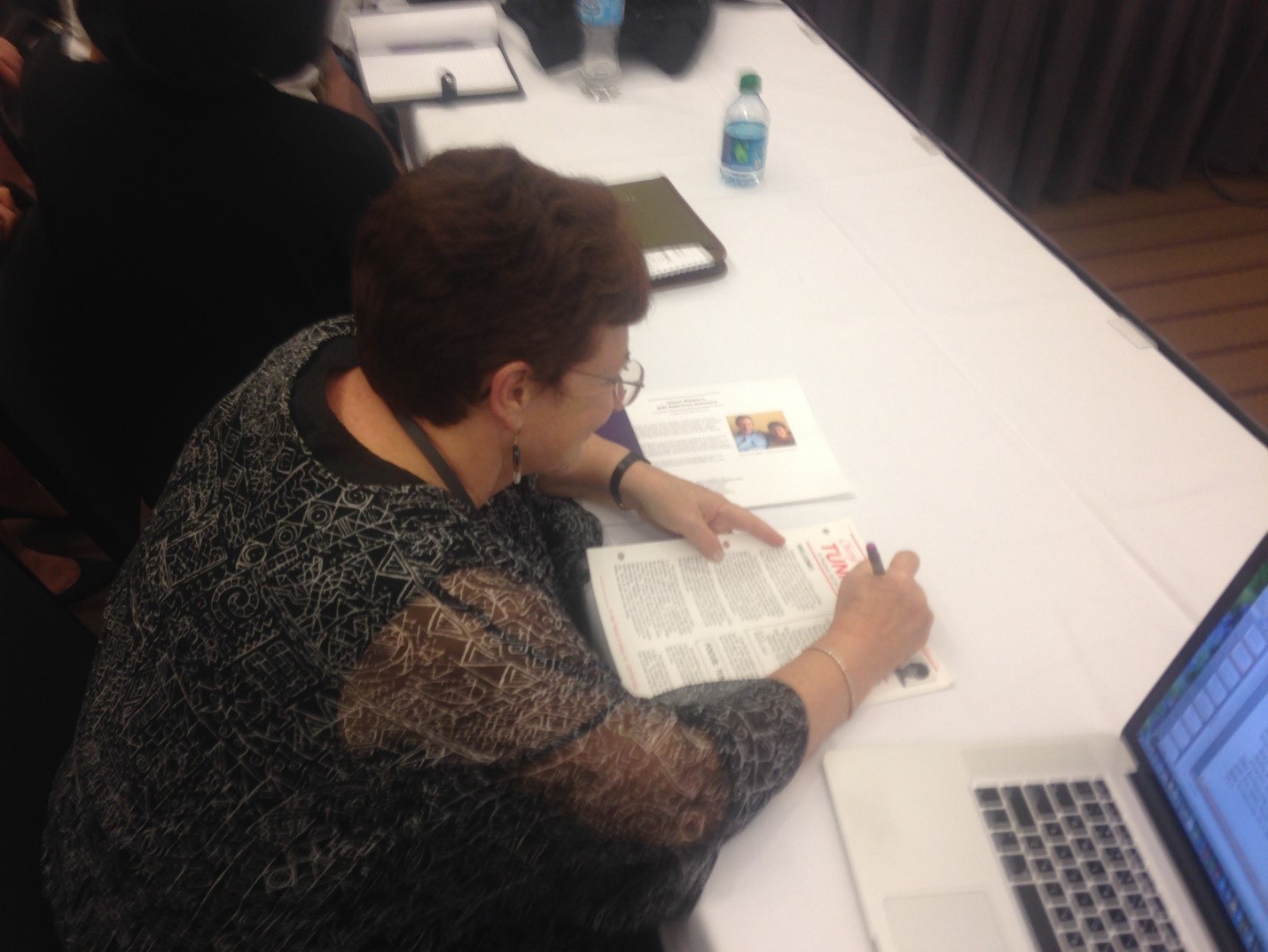 woman with short, curly, brown hair in a dark black blouse with shear sleeves and wearing glasses signing the first issue of the 'Tuning Letter' woman with short, curly, brown hair in a dark black blouse with shear sleeves and wearing glasses signing the first issue of the 'Tuning Letter'