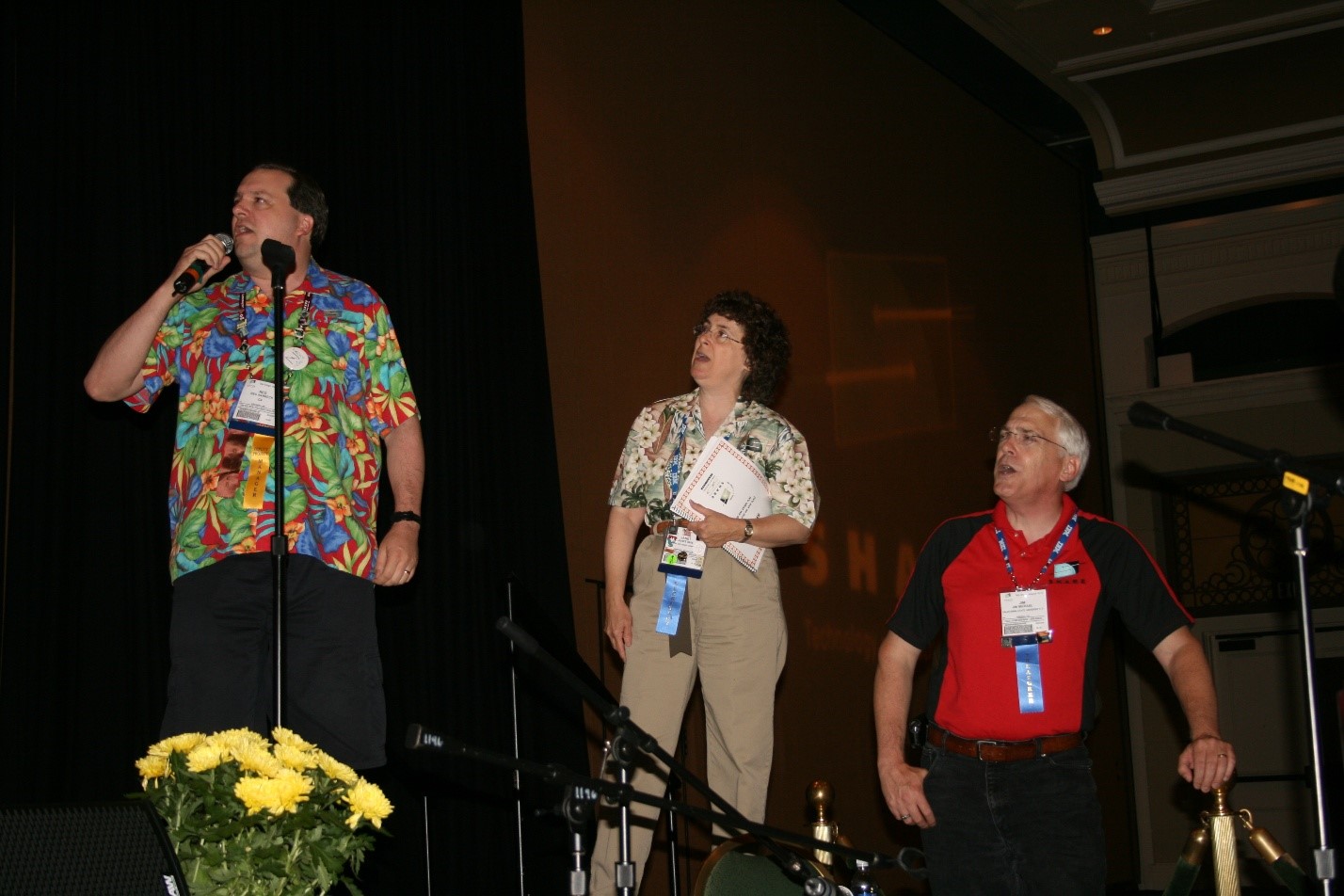 Sinalong at SHARE Orlando 2008 with Reg Harbeck in Hawaiian shirt leading the song, followed by past president Janet Sun in a floral shirt and tan pants and past vice president Jim Michael in a red shirt
